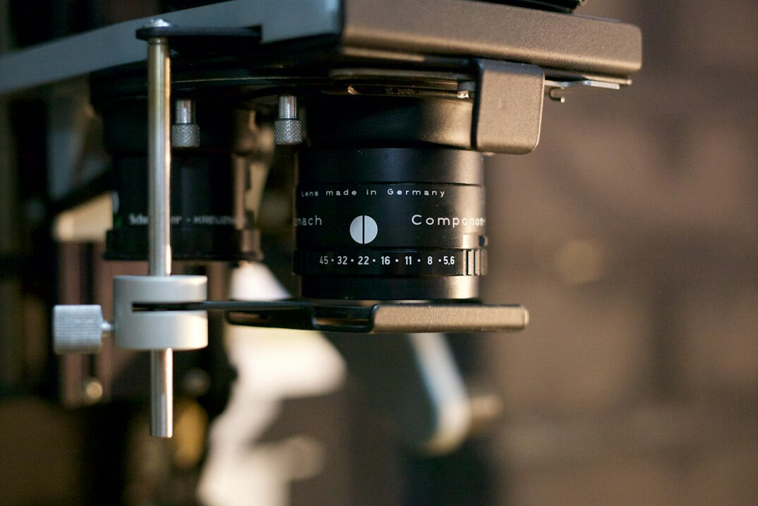 Television studio with a broadcast camera pointed at a presenter desk under bright studio lights
